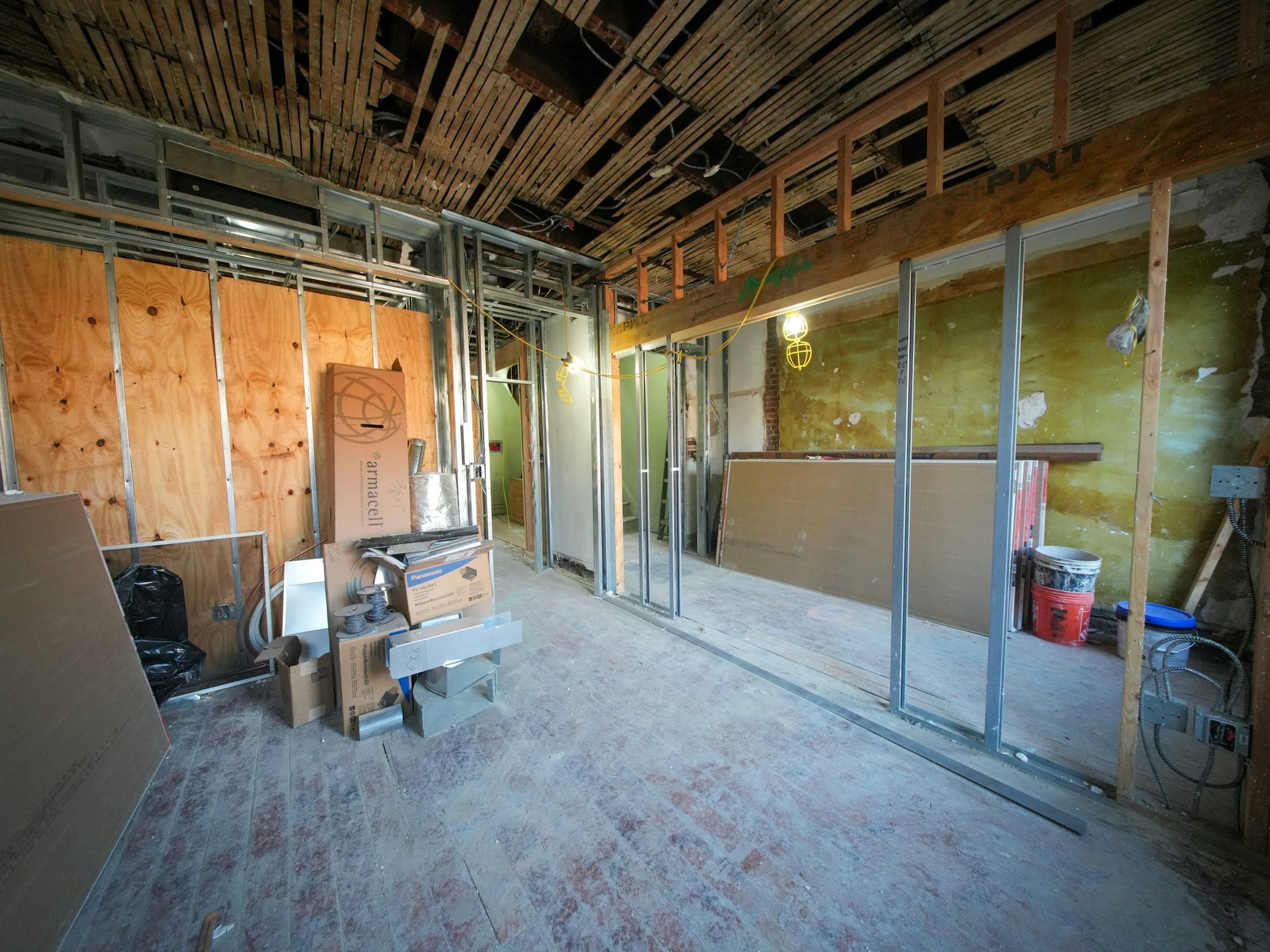 Et rum strippet ned til konstruktionen under en totalrenovering: synlige stolper, åbent loft og byggelys.